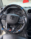 Timón para Toyota. (Instalado). En fibra de carbono y cuero forjado. Con mandos incluidos. Comodidad al manejar!
